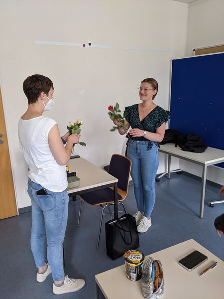 Klassenleitung überreicht an Schülerin eine Blume