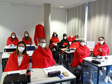 Schüler in warmen, roten Decken sitzen im Klassenzimmer