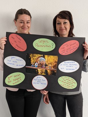 Zwei Teilnehmende an der HWA-Aktion „Für Demokratie und gegen Ausgrenzung“ halten ein selbstgebasteltes Plakat gegen Rassismus