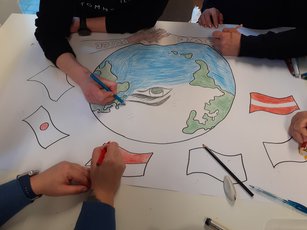 Teilnehmende der HWA-Aktion „Für Demokratie und gegen Ausgrenzung“ arbeiten an einem Plakat gegen Rassismus